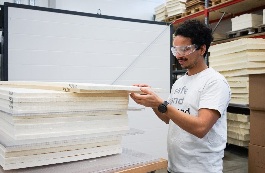 Smiling summer intern with mentors confidently holds an acoustic tile, showcasing dedication and enthusiasm in their role.